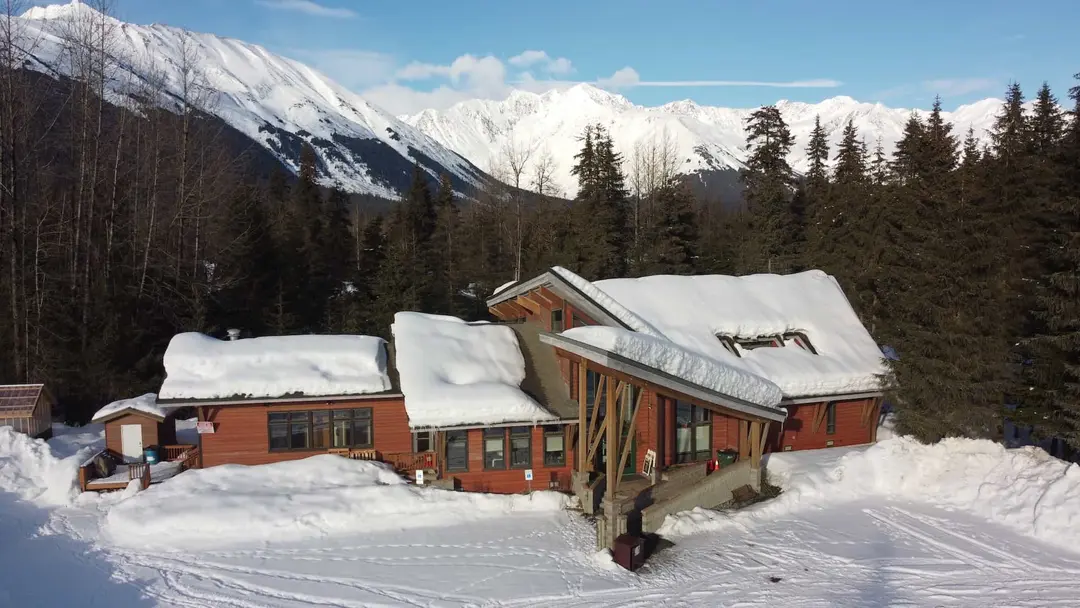 Aerial view of Girdwood Chapel, the parking lot, and the mountains